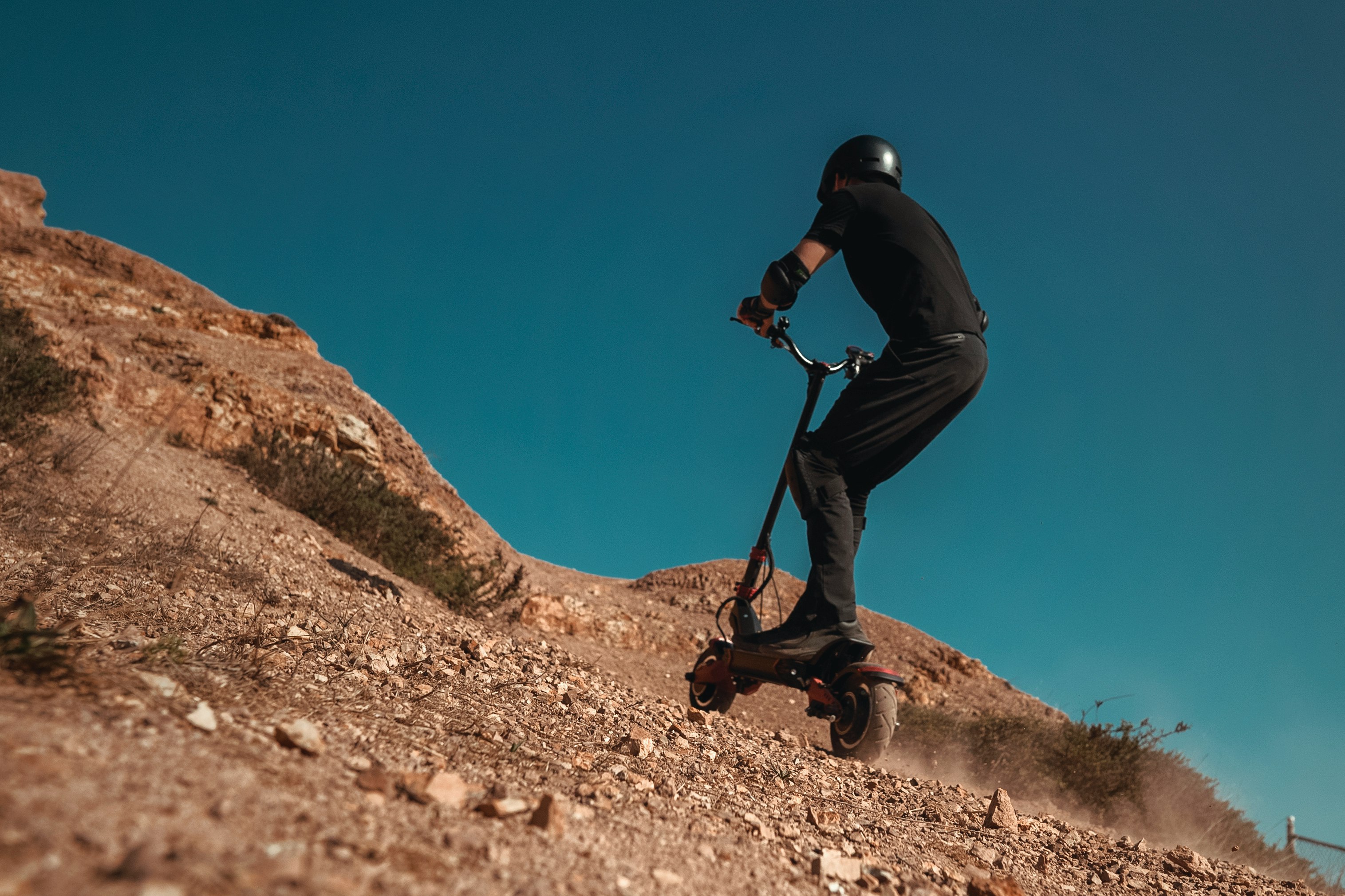 man in blue jacket and black pants climbing on brown rock mountain during daytime